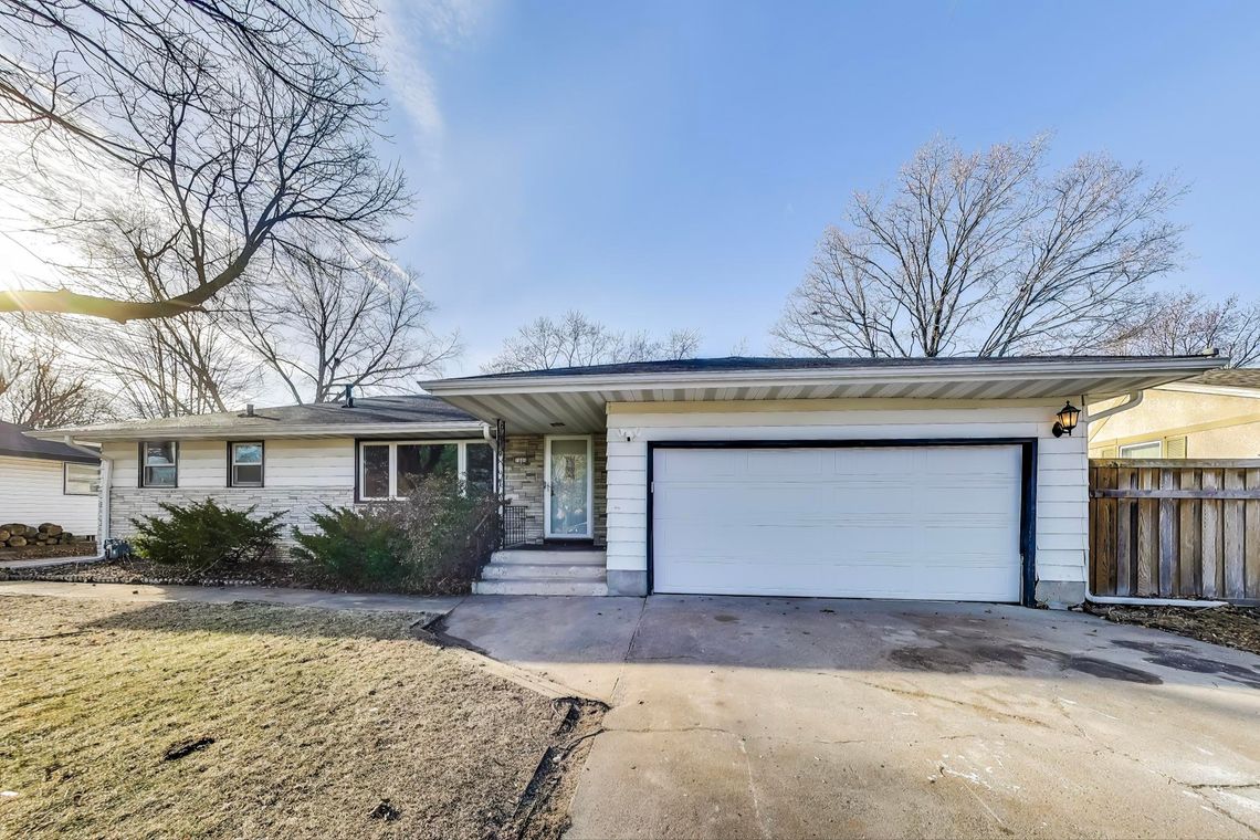 Front of a white single-storey home with an attached two-car garage and a wide concrete driveway.