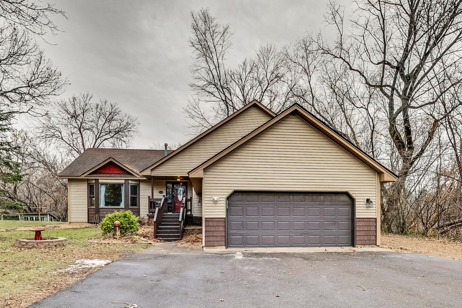 Front exterior with an attached two-car garage, wide driveway and wooden steps to a covered entry.