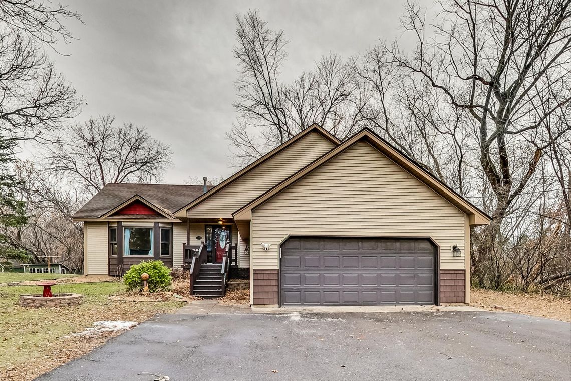 Front exterior with an attached two-car garage, wide driveway and wooden steps to a covered entry.