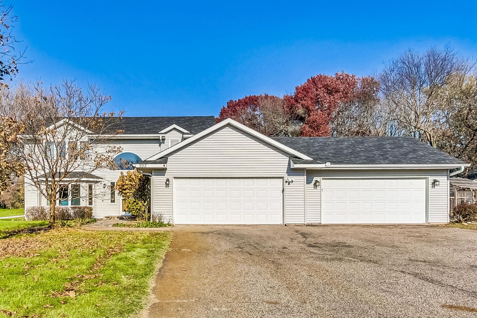 Two-storey house with pale siding, an arched entry window and two double garage doors.